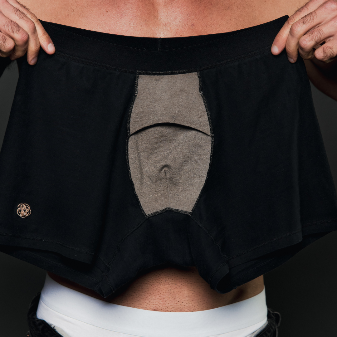 A man is holding up a black and grey boxer brief