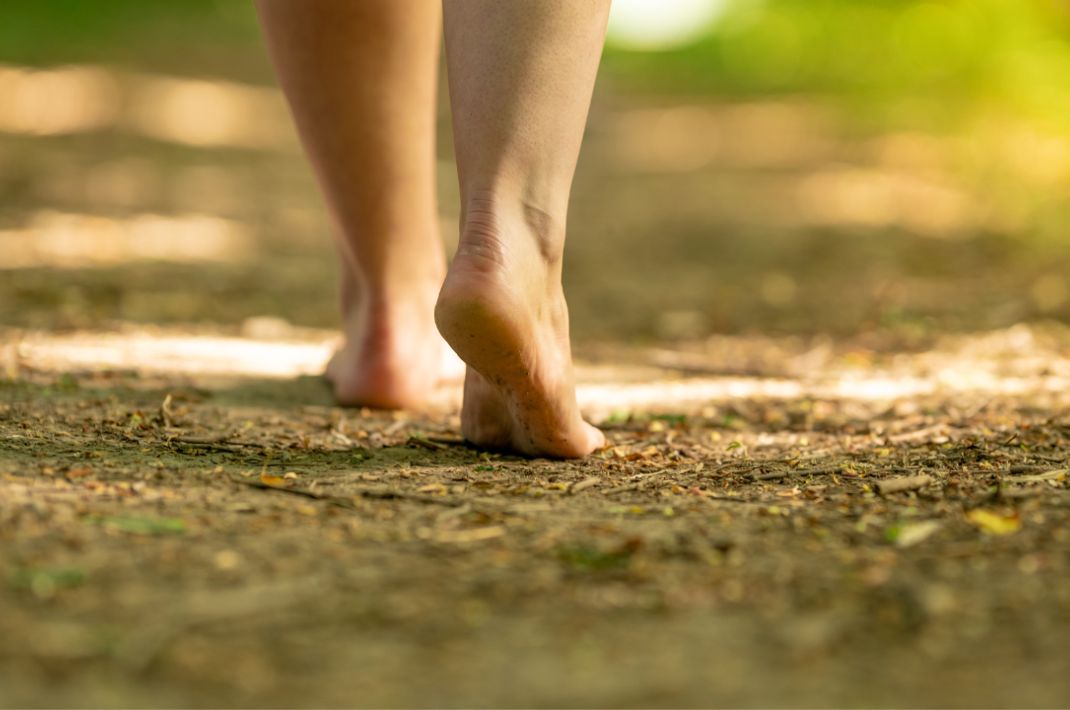A person walking barefoot along a trail in the woods