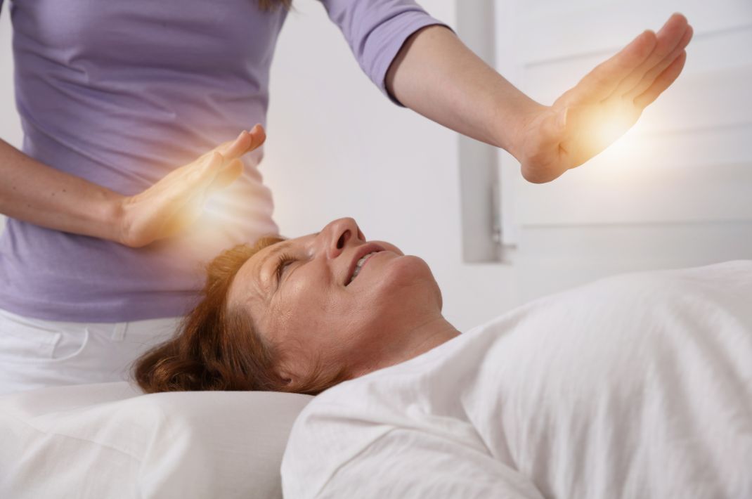A women lying down on her back having a Reiki therapy