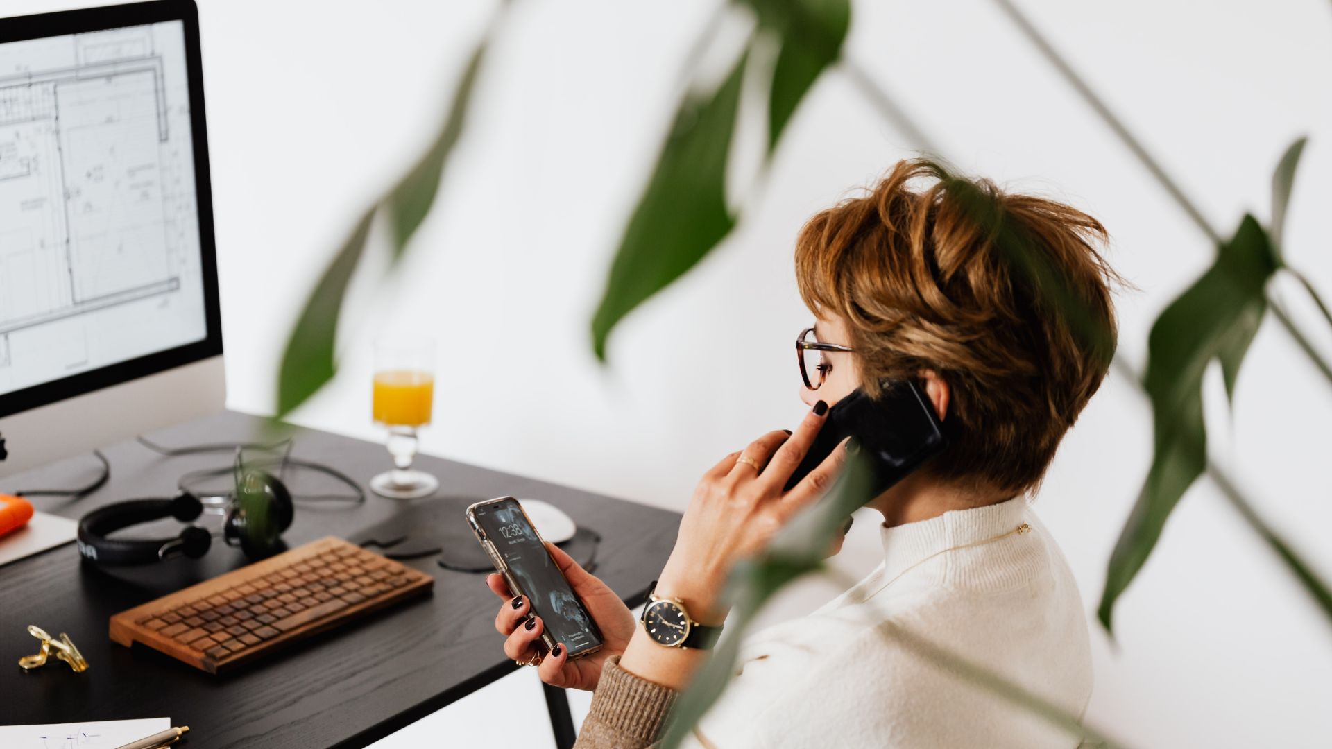 Busy female talking on smartphone and checking messages during work in contemporary office