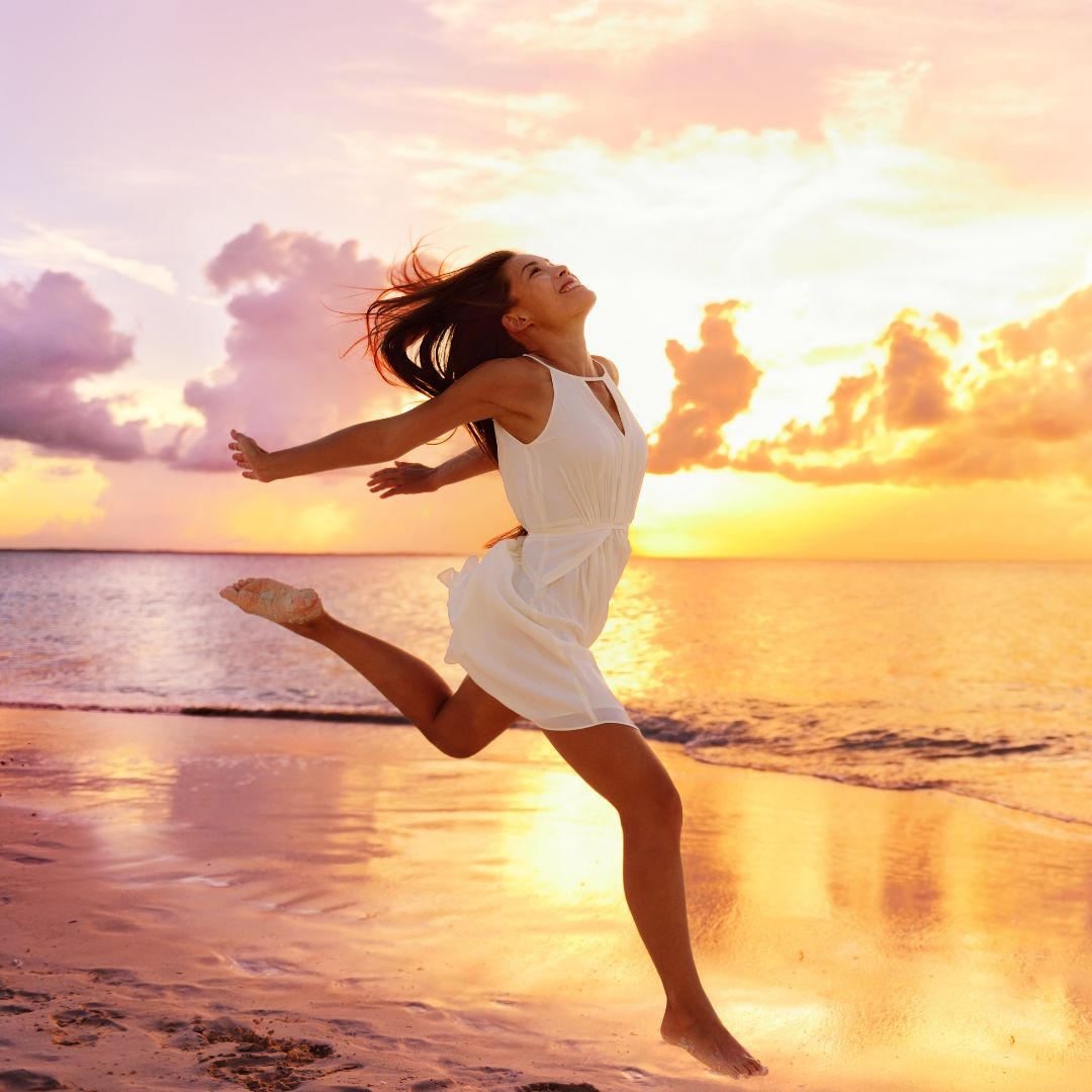 Asian woman blissful jumping on a peaceful beach