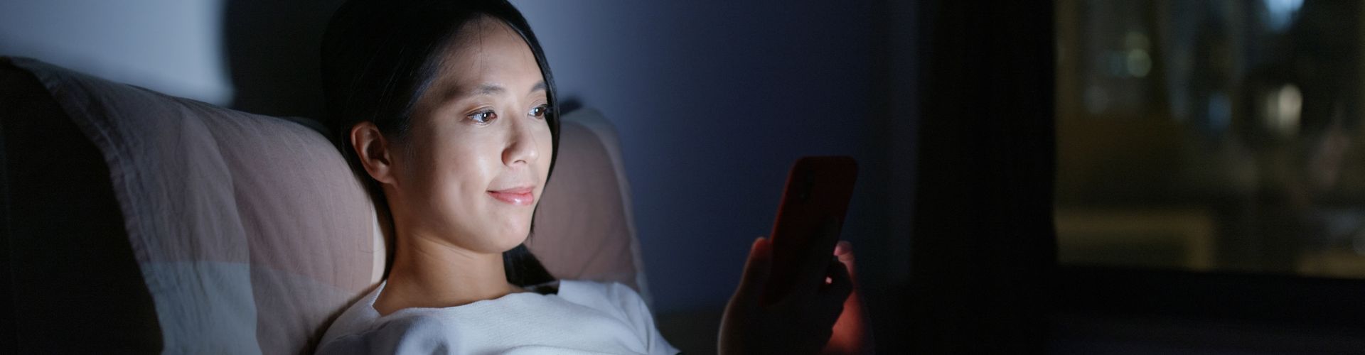 Woman Using Mobile Phone in Bed at Night
