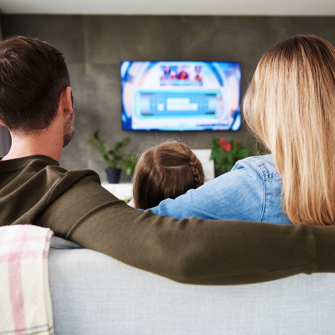 Rear view of family watching tv in living room