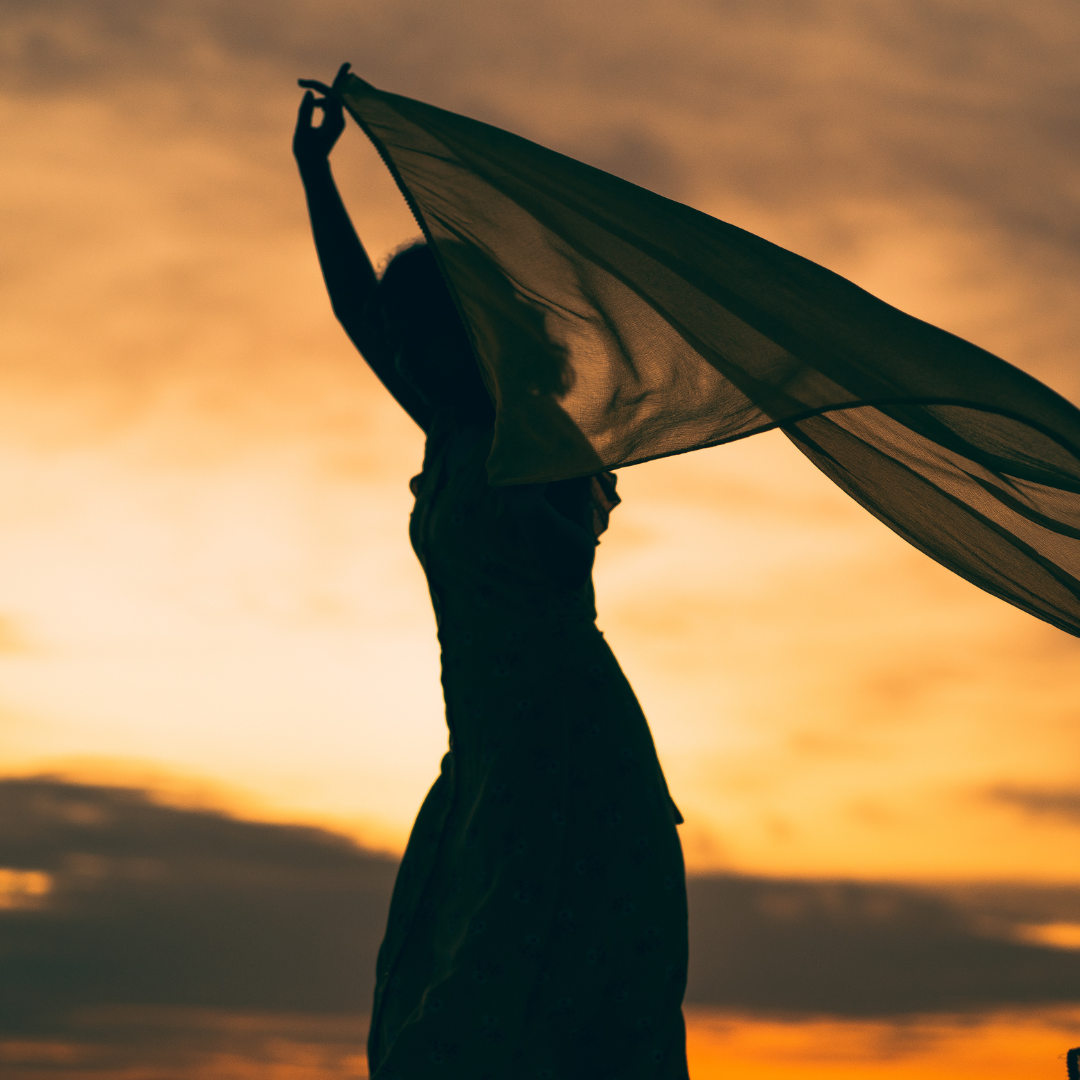 Silhouette of Woman Holding Scarf during Sunset