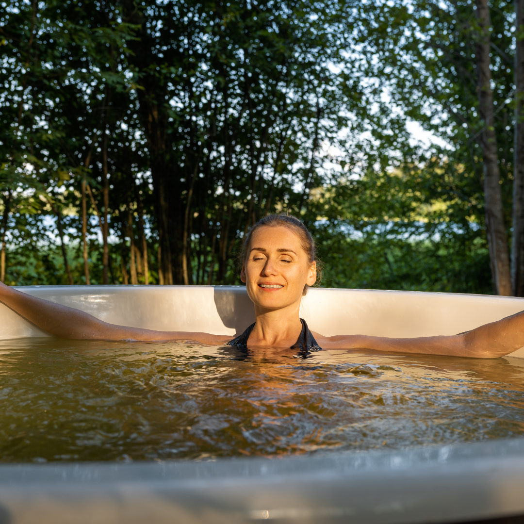 woman relaxing and enjoying outdoor hot tub at sunset in forest. nature spa
