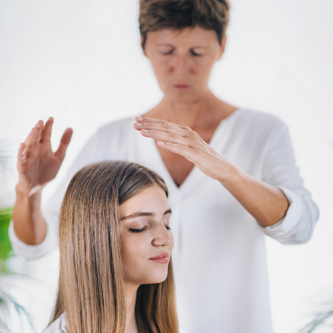 Midsection Of Therapist Giving Reiki Treatment To Teenage Girl On Head At Spa