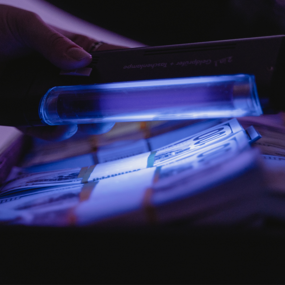 A Person Using UV Light on Money