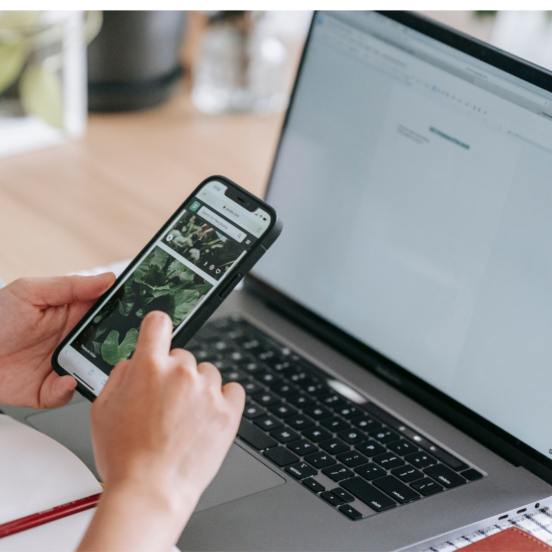 Faceless person browsing smartphone near laptop