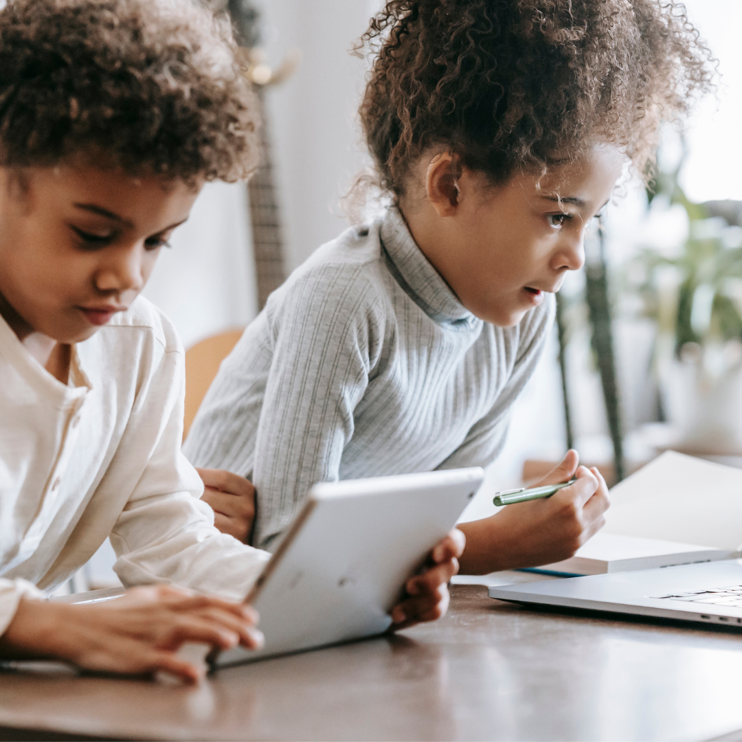 Concentrated black children using laptop and tablet at home