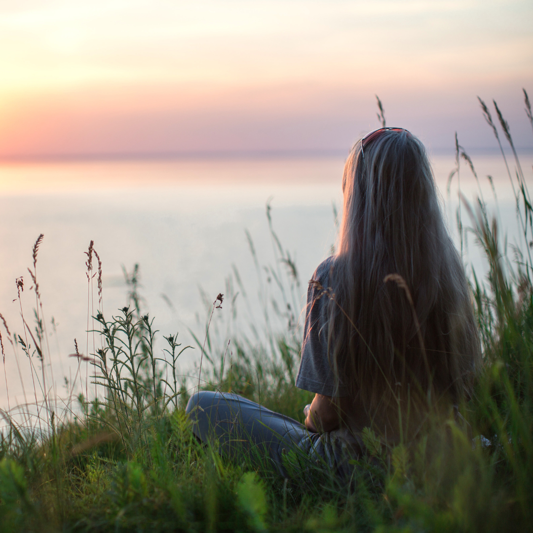 Photo of Woman Sitting on Grass During Golden Hour