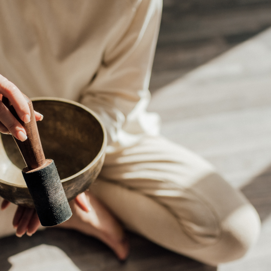 A Person Using a Tibetan Singing Bowl while Sitting on the Floor