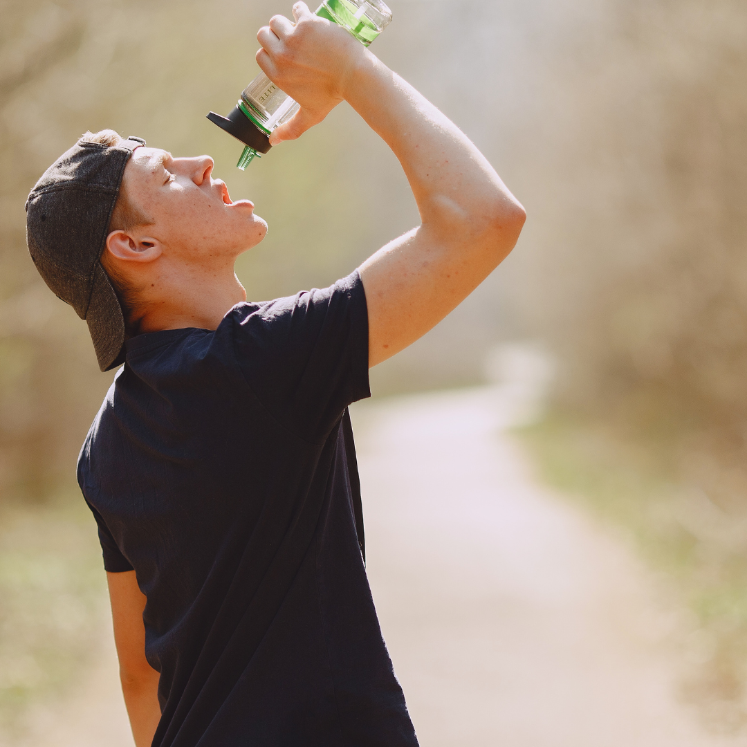 Thirsty man drinking water during training in park