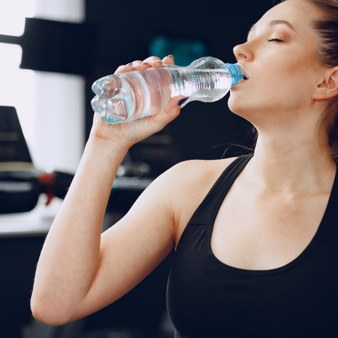 Young sporty woman drinking water in a gym