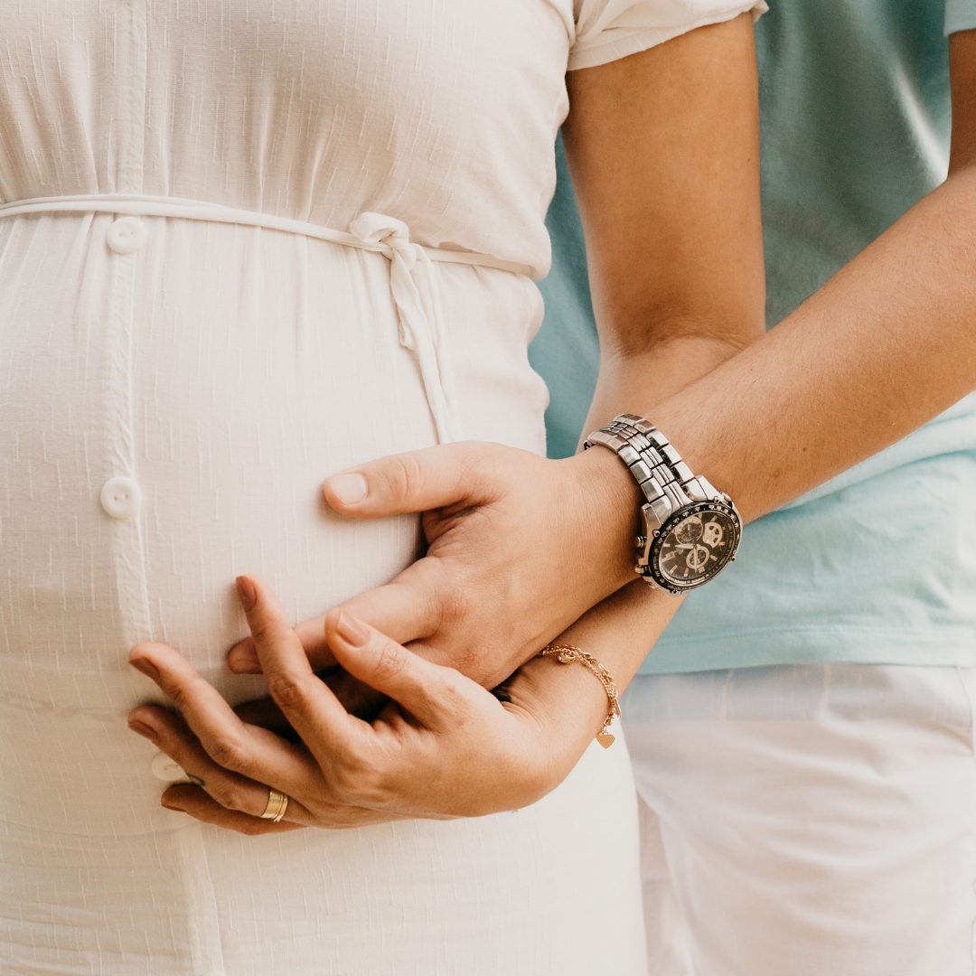 Crop pregnant woman embracing tummy with husband