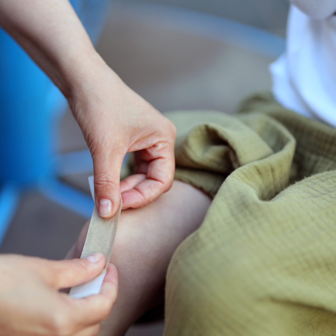 Close-up, sticking a band-aid on a child's leg wound.