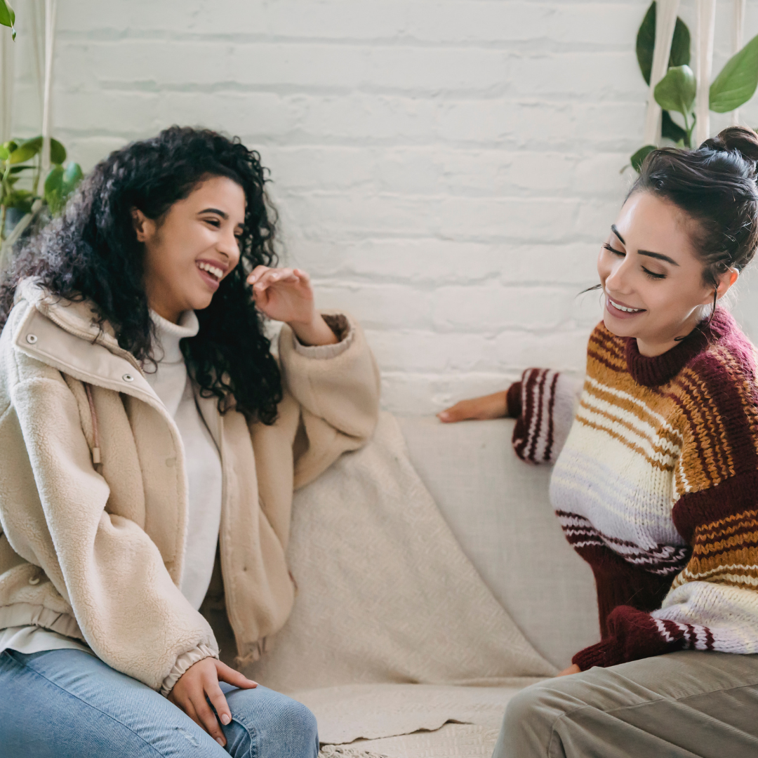 Happy young women sitting on couch and talking