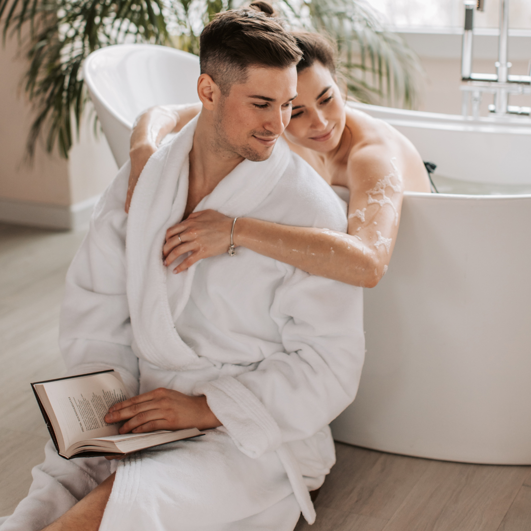 Man Sitting Beside a Bathtub with a Woman Bathing