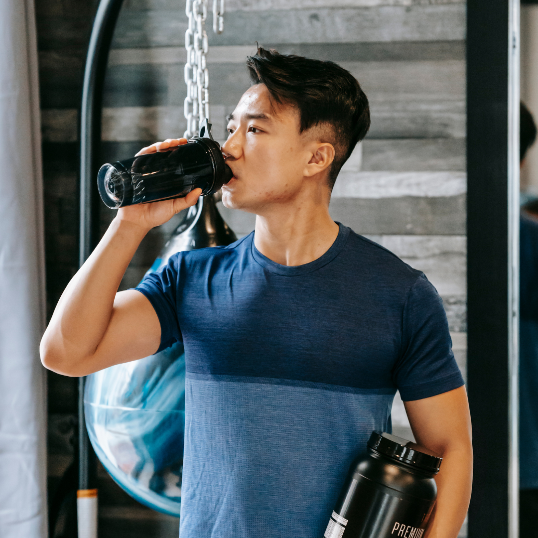 Asian athlete drinking water standing with bottle sports supplements