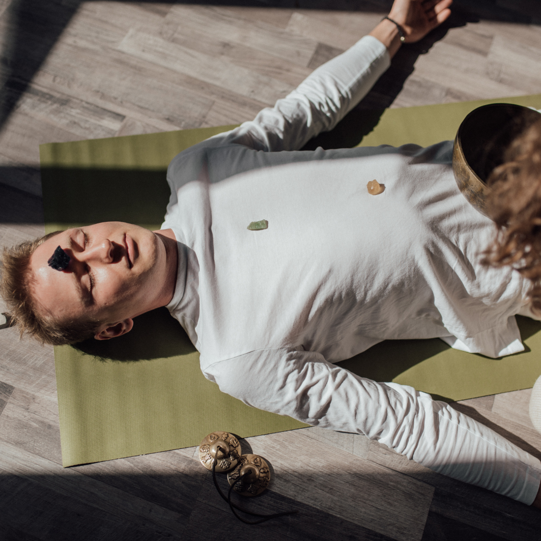 Man Lying Down on Floor with Healing Stone on Forehead