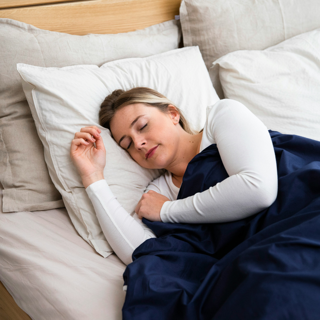 a woman sleeping on a bed with a blue blanket