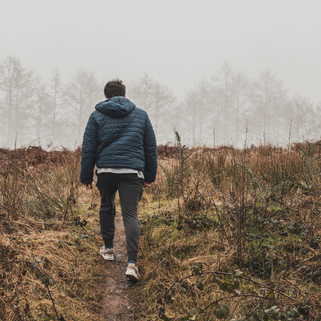 Man Wearing Blue Bubble Hoodie Jacket Walking on Green Grass Field