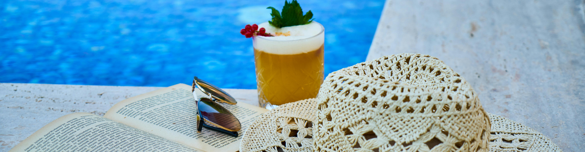 Beige Straw Hat, Book, Sunglasses, and Drink Beside Pool