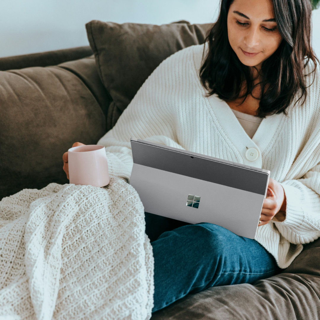 a woman sitting on a couch holding a laptop