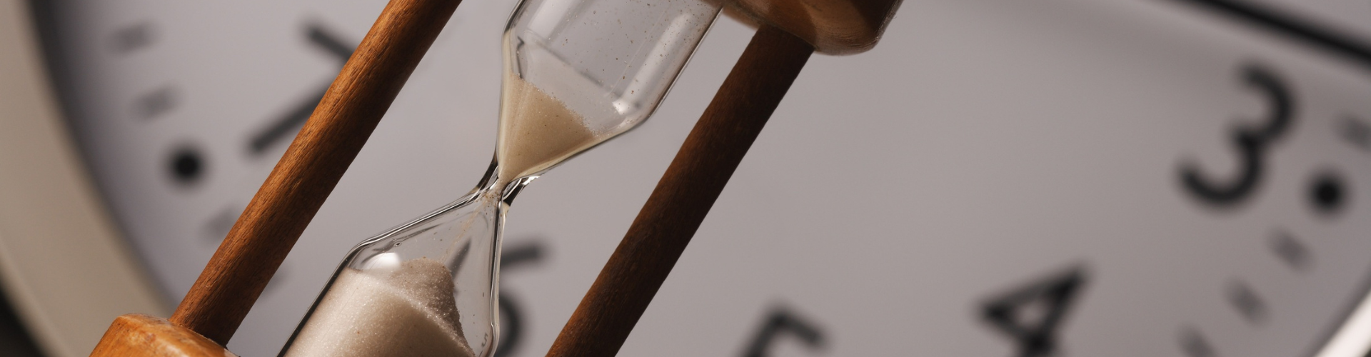 Close-Up of a Wooden Hourglass with Clock Background