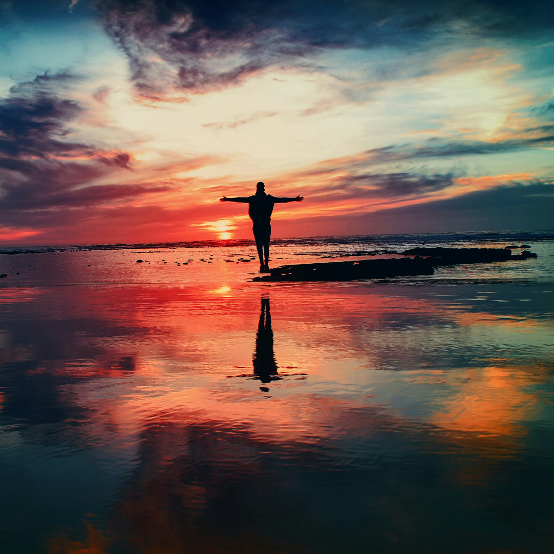 silhouette of person standing on rock surrounded by body of water