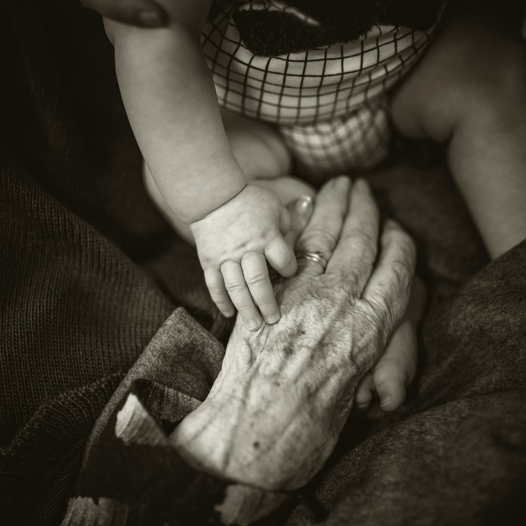 Older woman holding baby's hand