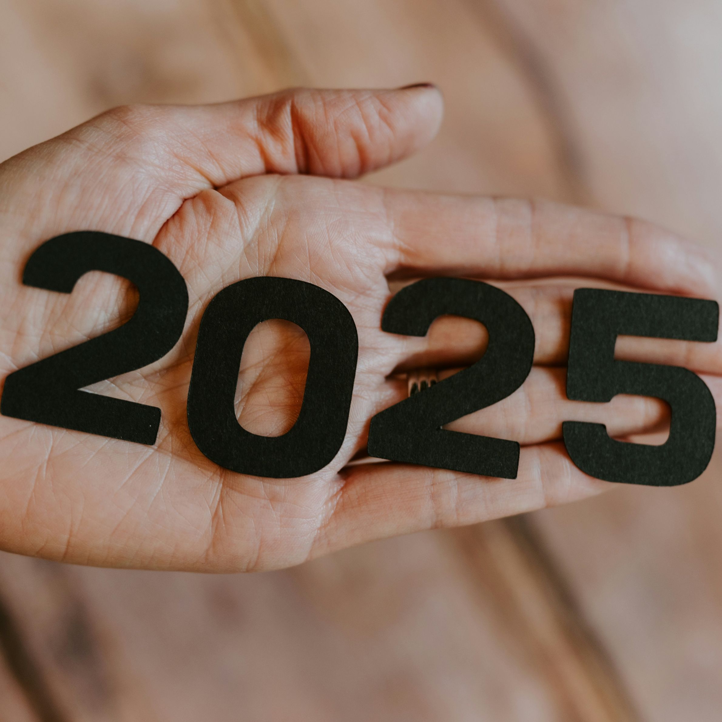 A person's hand holding the number twenty-twenty-five